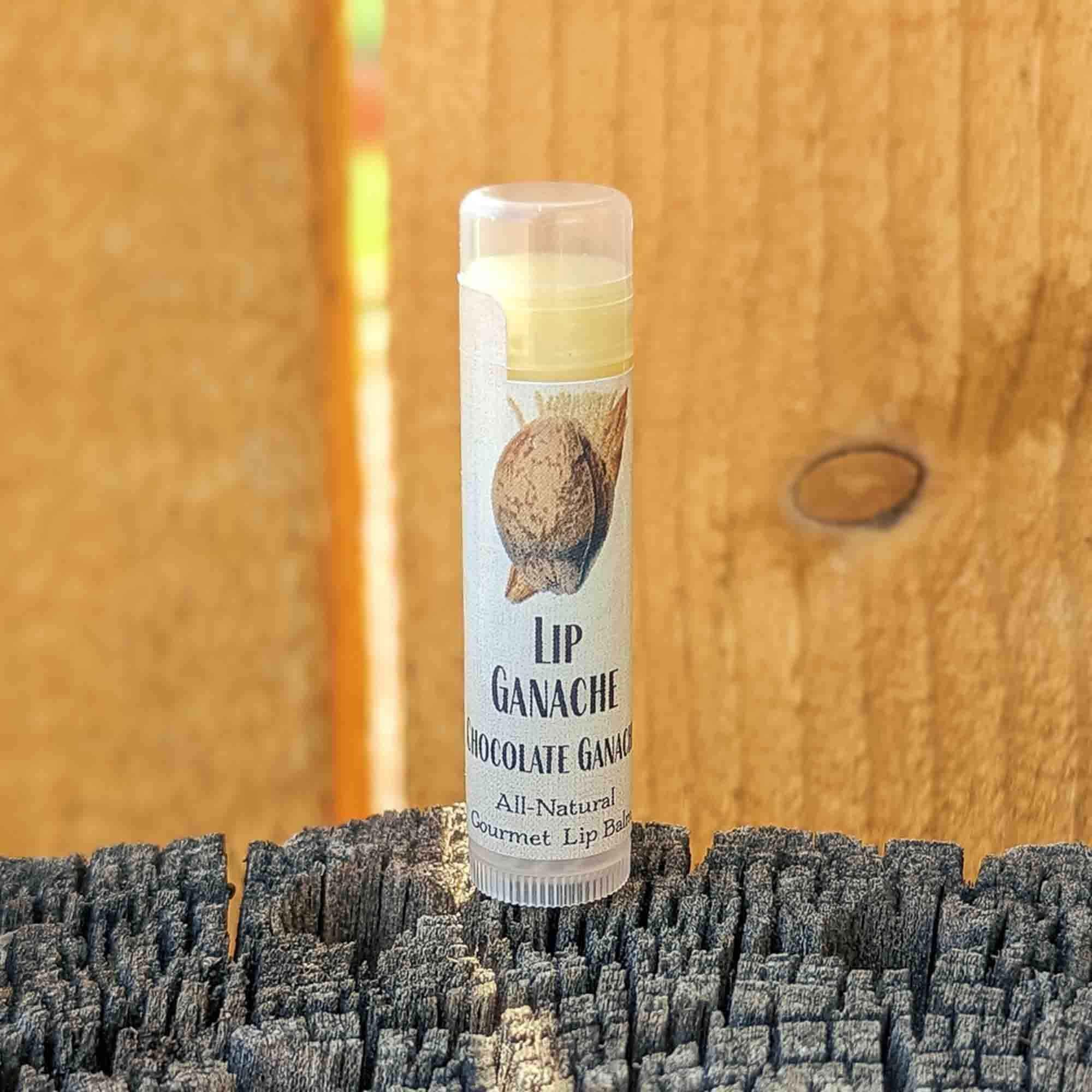 Tube of Lip Ganache Chocolate Ganache lip balm standing on a weathered wood post against a cedar fence